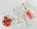 Rose champagne in bottle, bright glasses for wine and and red berries strawberry sparkling on light with shadows Royalty Free Stock Photo