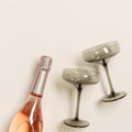 Rose champagne bottle and champagne glasses from tinted grey glass on beige table background. Minimal drink concept Royalty Free Stock Photo