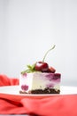 Rose cherry cheesecake with cream and fresh cherry on top served on a white plate over white background.