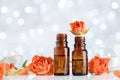 Rose essential oil bottles on white table with bokeh effect. Spa, aromatherapy, wellness, beauty background.