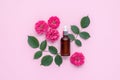 Rose essential oil for face massage. Glass bottle with pipette on pink table. Top view. Aromatherapy concept. Floral fragrance.