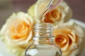 Rose essential oil falling from glass dropper into a bottle Royalty Free Stock Photo