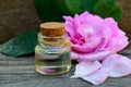 Rose essential oil in a glass bottle with fresh pink rose flower on old wooden table. Royalty Free Stock Photo