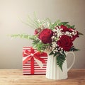 Rose flower bouquet and gift box on wooden table