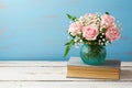 Rose flower bouquet in vase on old books over wooden background Royalty Free Stock Photo