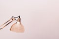 A rose gold folding lamp with a plain pink background