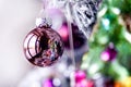 Rose gold pink glass Christmas ball bauble, snowy tree branch, green decoration, white bokeh bg Royalty Free Stock Photo