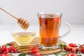 Rose hip tea in transparent cup with honey and fresh berries.