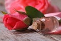 Rose oil in a glass bottle and pink flowers on wooden table Royalty Free Stock Photo