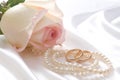 Rose, pearls and wedrings over white satin Royalty Free Stock Photo