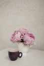 Rose peonies and a cup of coffee on a white table Royalty Free Stock Photo
