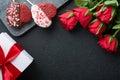 Rose red flowers, brownie cookies and chocolate candy on heart shaped, gift box with wine on black background. Valentines day, Mot Royalty Free Stock Photo
