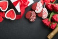 Rose red flowers, brownie cookies and chocolate candy on heart shaped, gift box with wine on black background. Valentines day, Mot Royalty Free Stock Photo