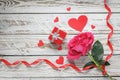 Rose with red paper hearts and gift box and ribbon on white wooden background. Love symbol concept. Royalty Free Stock Photo