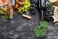 Rose red wine in bottles cheese, white pink and black grapes with vine plant on dark concrete background. Assortment Royalty Free Stock Photo