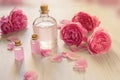 Rose water or oil bottles on wooden white background. Beautiful pink flowers and petals, aromatherapy and SPA concept Royalty Free Stock Photo