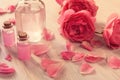 Rose water and oil in glass bottle with pink rose flowers on wooden background Royalty Free Stock Photo