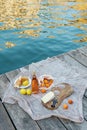 Rose wine, fruits and snacks on the wooden pier during picturesque picnic on the wooden dock
