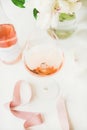 Rose wine in glass and bottle, pink ribbon, peony flowers