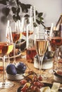 Rose wine glasses and bottles on table served for festive dinner party with different kinds of appetizers and fruits