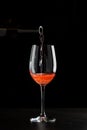 Rose wine pouring in a glass on black background