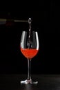 Rose wine pouring in a glass on black background Royalty Free Stock Photo