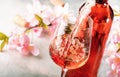 Rose wine pouring out of the bottle, gray bakcground, pink flowers. Rosado, rosato or blush wine tasting in wineshop, bar concept Royalty Free Stock Photo