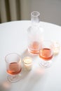 Rose wine in trendy ribbed wineglasses and decanter on white table Royalty Free Stock Photo