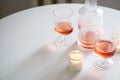 Rose wine in trendy ribbed wineglasses and decanter on white table Royalty Free Stock Photo