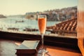 Rose wine and vintage book on window sill with cityscape of Porto, Portugal. Boats on river Douro and buildings