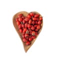 Rosehip berries in a wooden bowl in a heart background isolated on a white background. Berries for making vitamin tea or drink