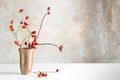 Rosehip branches in a stoneware vase on a white table in front o