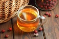 Rosehip brewed tea in a glass cup with red berry near on wooden rustic table, natural remedy and support for heart disease