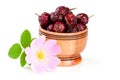 Rosehip flowers with leaf and rosehip berries in a wooden bowl isolated on white background