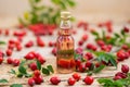 Rosehip oil in glass bottle with berries around from close up