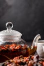 Rosehip tea. Vitamin drink. A glass teapot and cups with a freshly brewed vitamin rosehip drink on a dark background. Copy space