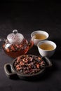 Rosehip tea. Vitamin drink. Glass teapot and cups with freshly brewed vitamin rose hips, dark mood. Copy space