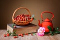 Rosehip in wicker baskets, book, rose and a teapot Royalty Free Stock Photo