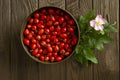 Rosehips in vintage brass bowl and a branch of rosehip bush with a pink rosehip flower