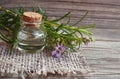 Rosemary essential oil in a glass bottle with fresh green rosemary herb on old wooden table for spa, aromatherapy and bodycare. Royalty Free Stock Photo