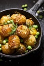 Rosemary and garlic roast potatoes with green peas on a cast iron pan