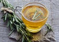 Rosemary herbal tea in a glass cup with fresh green rosemary herb on rustic wooden background. Royalty Free Stock Photo