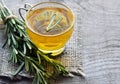 Rosemary herbal tea in a glass cup with fresh green rosemary herb on rustic wooden background. Royalty Free Stock Photo