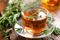 Rosemary tea in glass tea cup on rustic wooden table closeup. Herbal vitamin tea