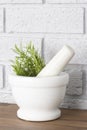 Rosemary in a white granite pestle and mortar.  Grey brick background Royalty Free Stock Photo