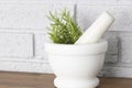 Rosemary in a white granite pestle and mortar.  Grey brick background Royalty Free Stock Photo