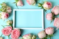 Roses and empty frame on blue background, space for text Royalty Free Stock Photo