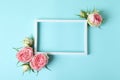 Roses and empty frame on blue background, space for text Royalty Free Stock Photo