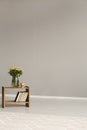 Roses in vase on wooden shelf with books, copy space on empty grey wall