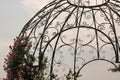 ROSES GROWING AND FLOWERING UP THE SIDE OF A DECORATIVE METAL DOME Royalty Free Stock Photo